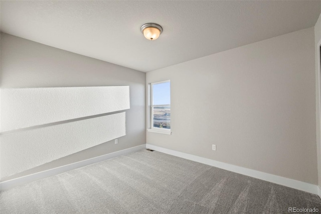 carpeted spare room featuring visible vents and baseboards