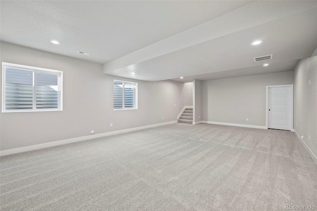 below grade area featuring baseboards, visible vents, light colored carpet, stairway, and recessed lighting