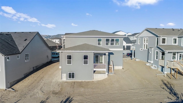 rear view of house with a residential view and stucco siding