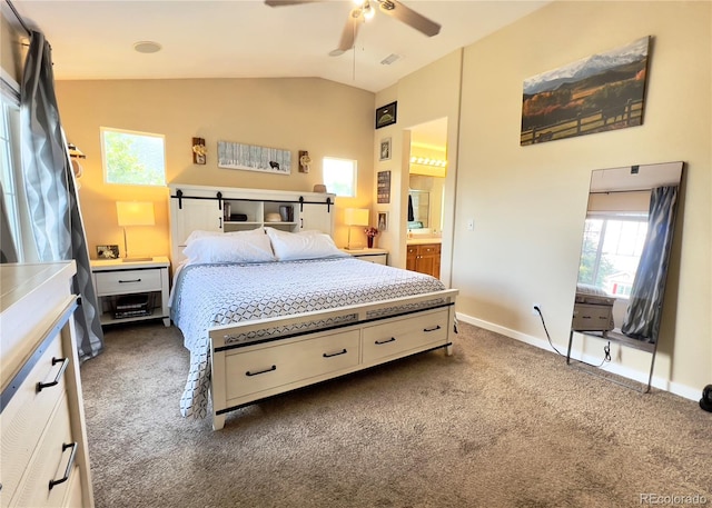 bedroom featuring ceiling fan, ensuite bathroom, lofted ceiling, and dark colored carpet