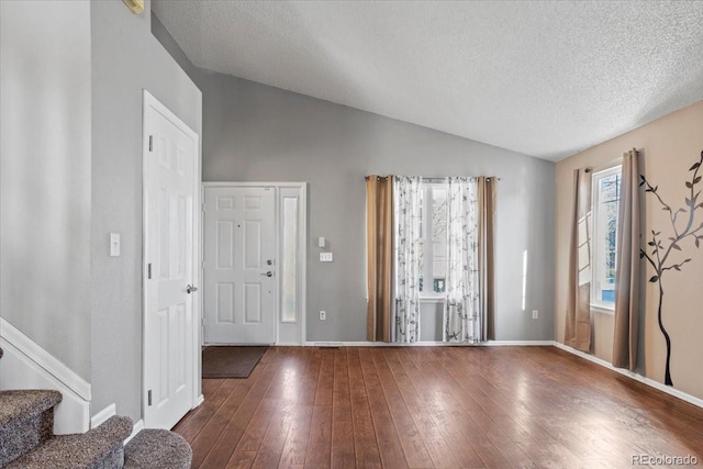 foyer featuring lofted ceiling, dark hardwood / wood-style floors, and a textured ceiling