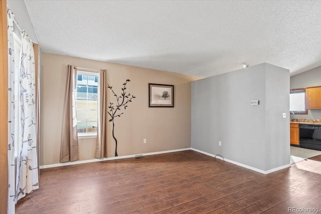 spare room featuring dark wood-type flooring and a textured ceiling