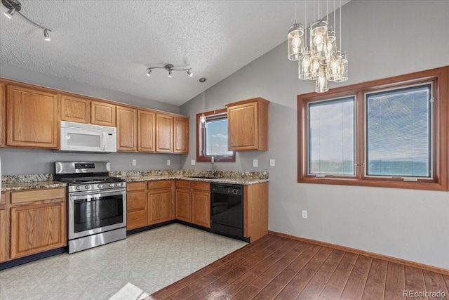 kitchen featuring vaulted ceiling, dishwasher, sink, hanging light fixtures, and stainless steel gas range oven