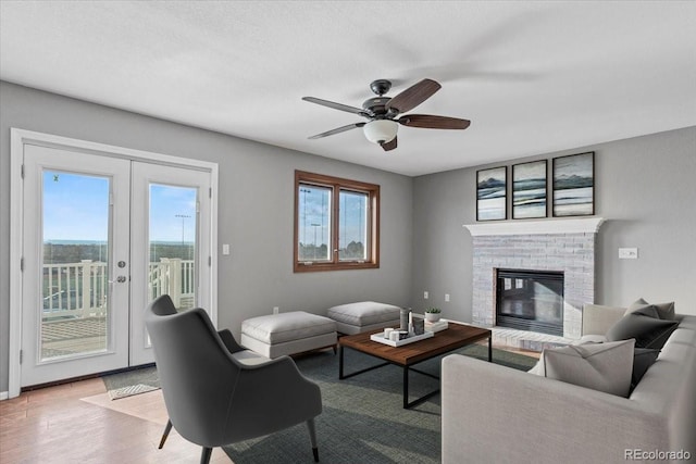 living room featuring light hardwood / wood-style flooring, a wealth of natural light, a fireplace, and french doors