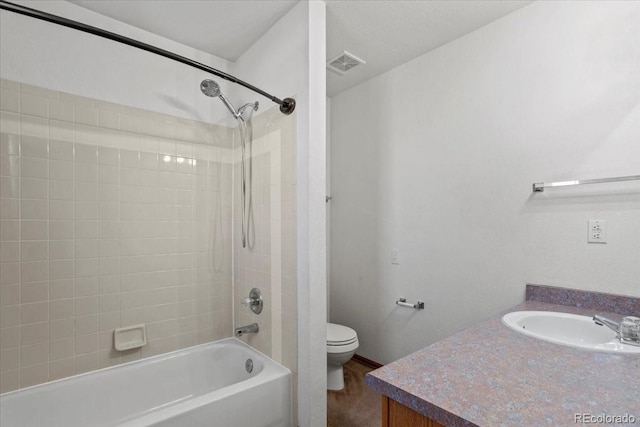 full bathroom with tiled shower / bath, vanity, and toilet