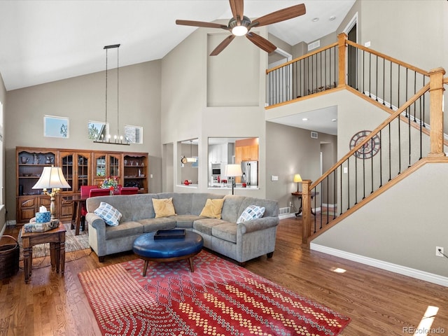 living area featuring wood finished floors, baseboards, a chandelier, stairway, and ceiling fan