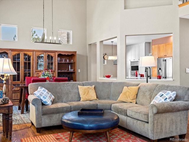 living area with a high ceiling, a chandelier, and wood finished floors