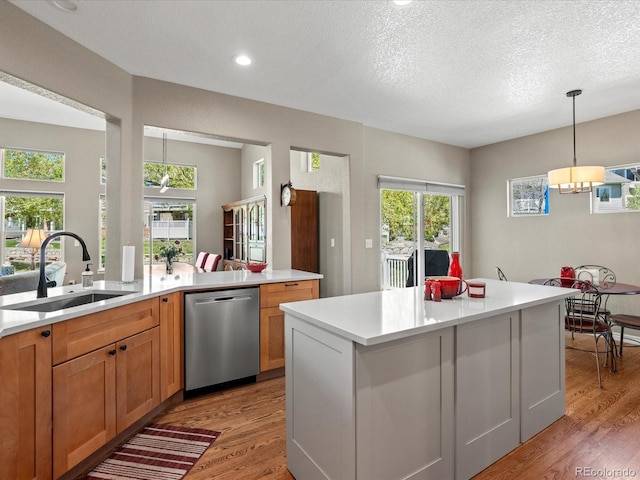 kitchen with stainless steel dishwasher, a sink, light wood-type flooring, light countertops, and plenty of natural light