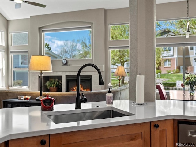 kitchen with a sink, a tiled fireplace, healthy amount of natural light, and light countertops