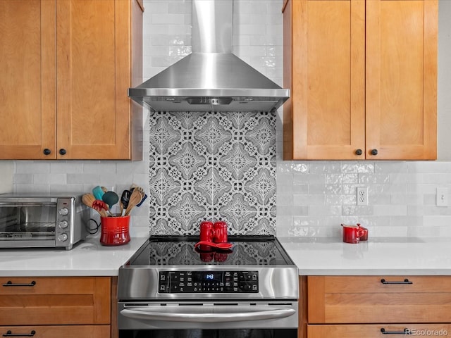 kitchen featuring wall chimney range hood, stainless steel range with electric cooktop, tasteful backsplash, and light countertops