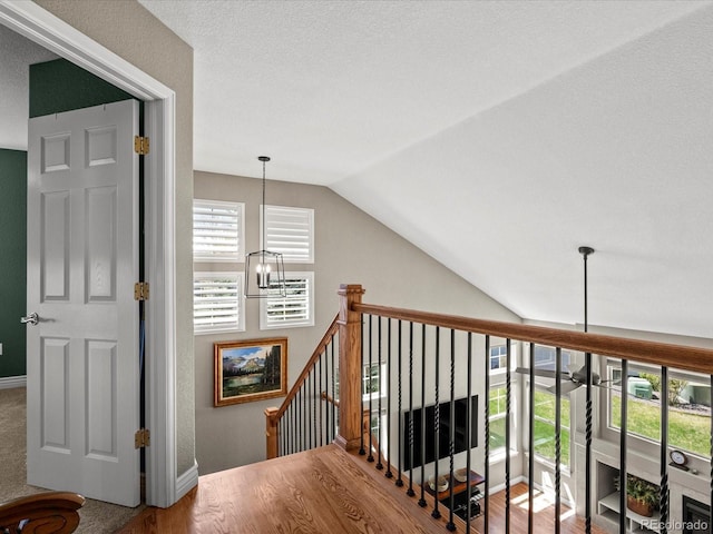hallway featuring lofted ceiling, an upstairs landing, and baseboards