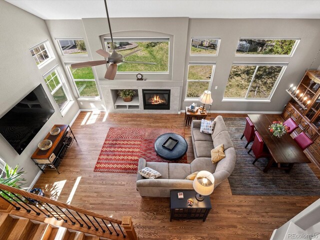 living room featuring plenty of natural light, a fireplace, ceiling fan, and wood finished floors