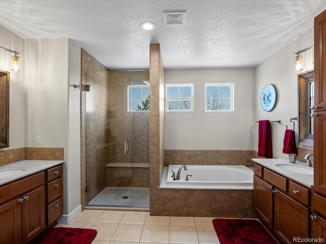 full bathroom with plenty of natural light, a stall shower, a garden tub, two vanities, and a textured ceiling