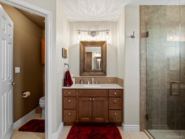 full bath featuring a stall shower, tile patterned flooring, toilet, vanity, and baseboards