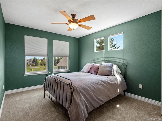 bedroom with carpet, baseboards, a ceiling fan, and a textured wall