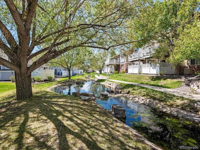 view of grassy yard with a residential view and a garden pond