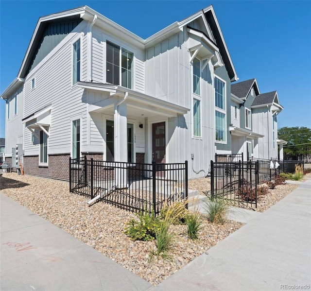 view of front of house with fence, board and batten siding, and brick siding