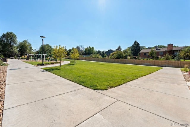 view of home's community with a lawn and fence