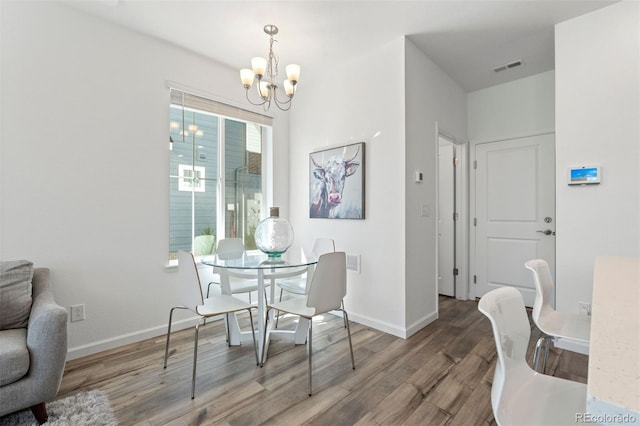 dining area featuring a chandelier, wood finished floors, visible vents, and baseboards