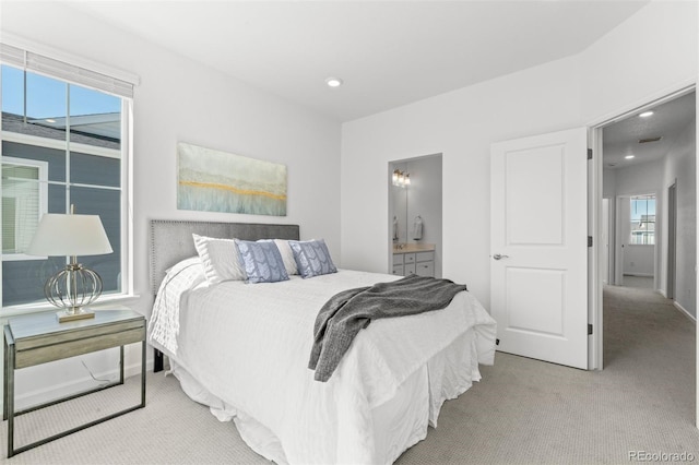 bedroom featuring light carpet, ensuite bath, baseboards, and recessed lighting