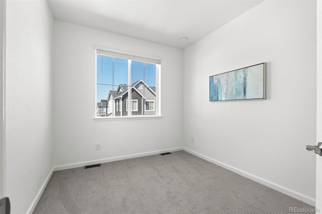 carpeted spare room featuring visible vents and baseboards