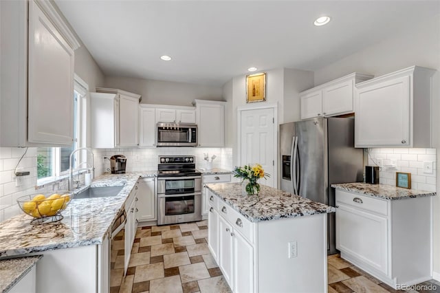 4578 Quandary Peak St, Brighton, CO 80601 - kitchen featuring stainless steel appliances, white cabinets, tasteful backsplash, a sink, and a kitchen island