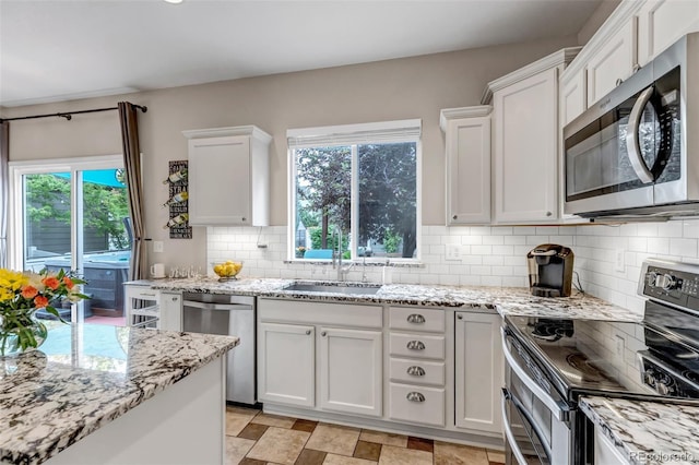 4578 Quandary Peak St, Brighton, CO 80601 - kitchen with stainless steel appliances, white cabinets, decorative backsplash, a sink, and light stone countertops