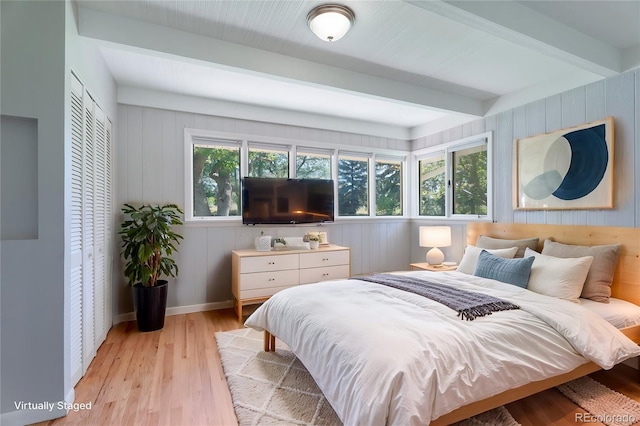 8813 Baseline Rd, Lafayette, CO 80026 - bedroom featuring beamed ceiling, light wood-style flooring, a closet, wooden walls, and baseboards