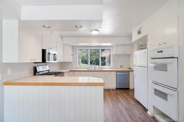 8813 Baseline Rd, Lafayette, CO 80026 - kitchen with stainless steel appliances, a sink, a peninsula, white cabinetry, and light wood-style floors