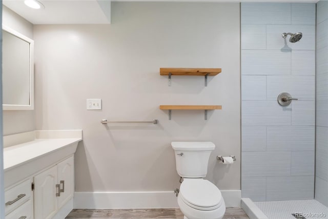 8813 Baseline Rd, Lafayette, CO 80026 - full bathroom featuring baseboards, a tile shower, toilet, vanity, and wood finished floors