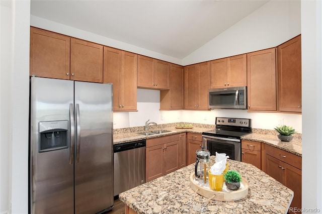 804 Summer Hawk Dr Unit 7301, Longmont, CO 80504 - kitchen featuring a sink, brown cabinets, lofted ceiling, appliances with stainless steel finishes, and light stone countertops