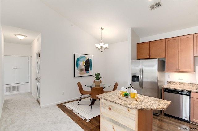 804 Summer Hawk Dr Unit 7301, Longmont, CO 80504 - kitchen with a notable chandelier, stacked washer and clothes dryer, stainless steel appliances, and visible vents