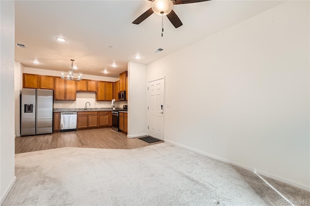 kitchen with brown cabinetry, visible vents, stainless steel appliances, and a sink