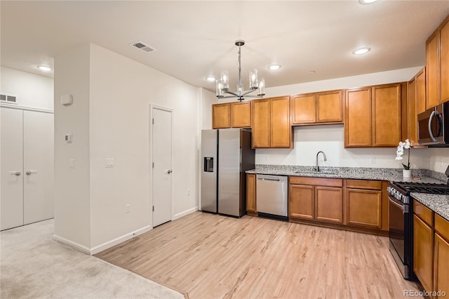 kitchen with hanging light fixtures, appliances with stainless steel finishes, brown cabinets, and a sink