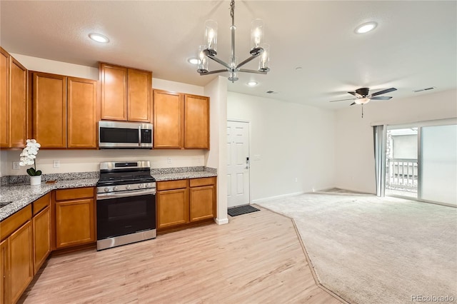 kitchen featuring visible vents, brown cabinets, open floor plan, stainless steel appliances, and light countertops