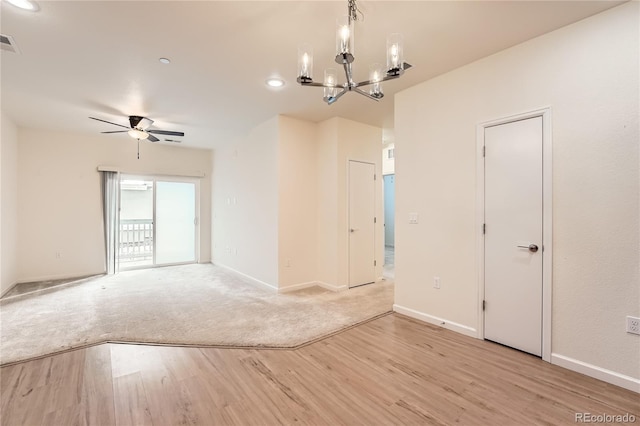 unfurnished room featuring light wood-style flooring, visible vents, baseboards, and ceiling fan with notable chandelier