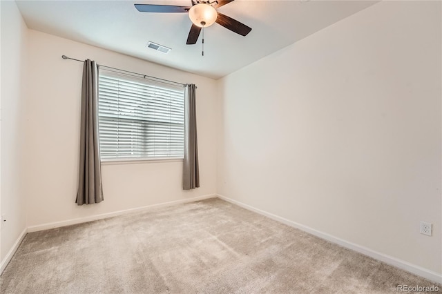 empty room with baseboards, visible vents, ceiling fan, and light colored carpet