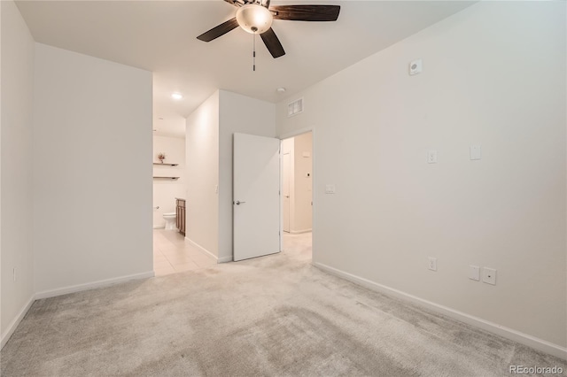 spare room with a ceiling fan, light colored carpet, visible vents, and baseboards