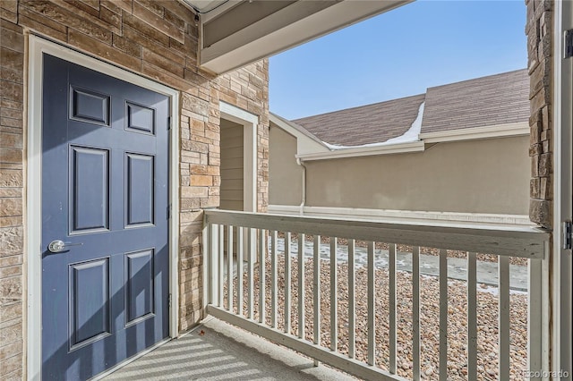 view of exterior entry with stone siding and roof with shingles