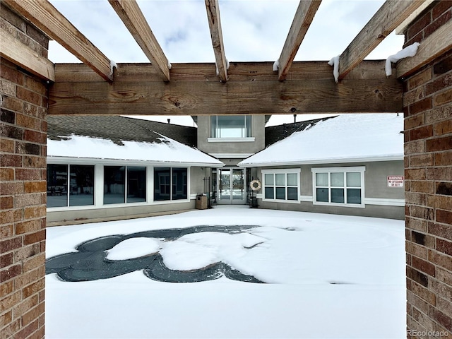 snow covered back of property with brick siding and stucco siding