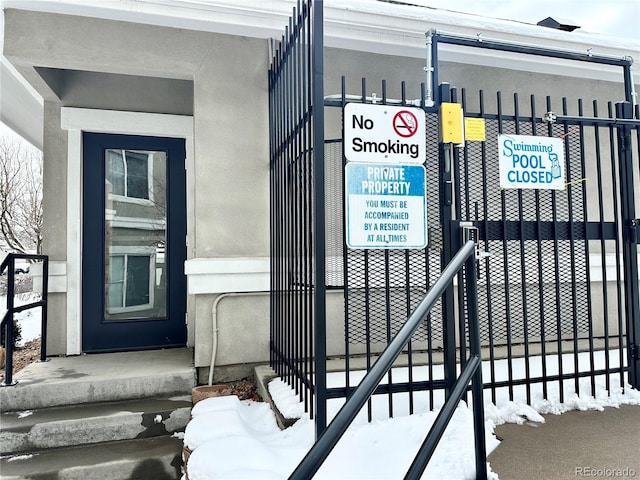 snow covered property entrance with stucco siding