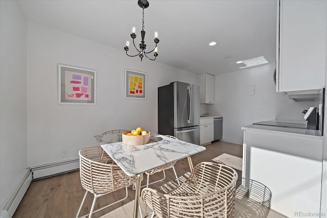 kitchen featuring white cabinetry, a baseboard radiator, an inviting chandelier, appliances with stainless steel finishes, and hardwood / wood-style flooring