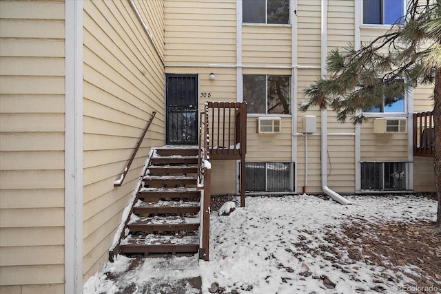 snow covered property entrance featuring an AC wall unit