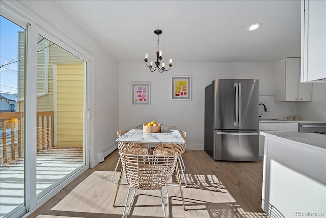 dining space featuring light wood-type flooring, a baseboard radiator, an inviting chandelier, and a healthy amount of sunlight