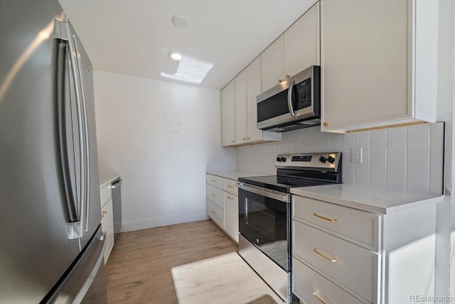 kitchen featuring backsplash, light stone counters, stainless steel appliances, white cabinets, and light hardwood / wood-style floors