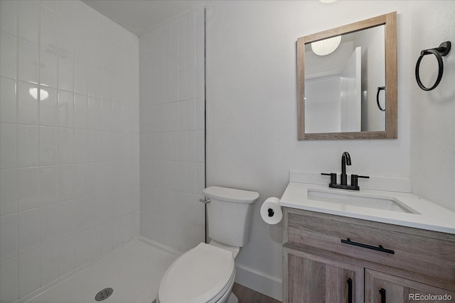 bathroom featuring tiled shower, hardwood / wood-style floors, vanity, and toilet