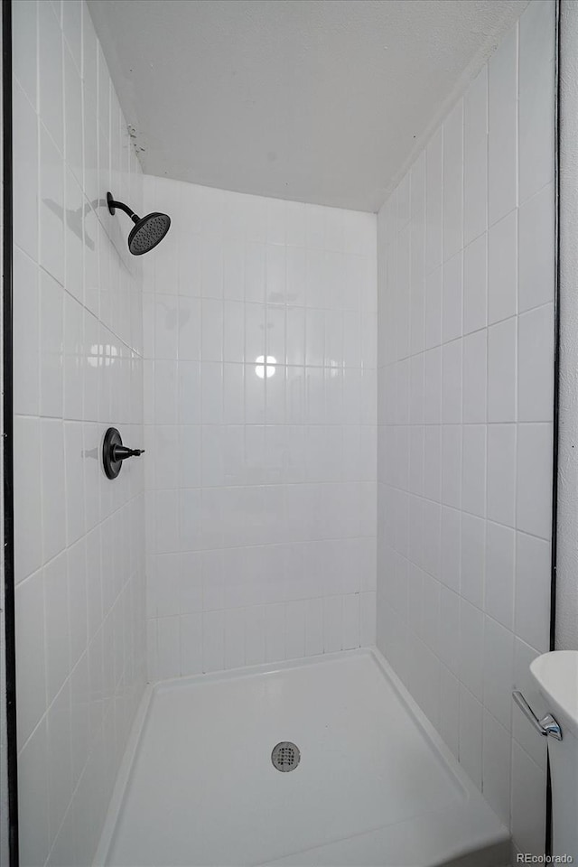 bathroom featuring a tile shower and toilet