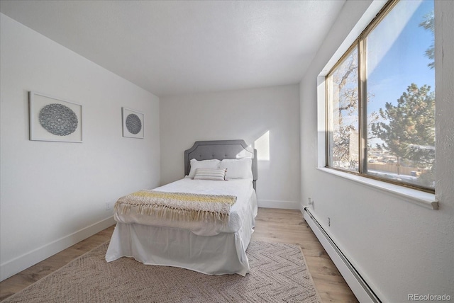 bedroom featuring baseboard heating and light hardwood / wood-style flooring