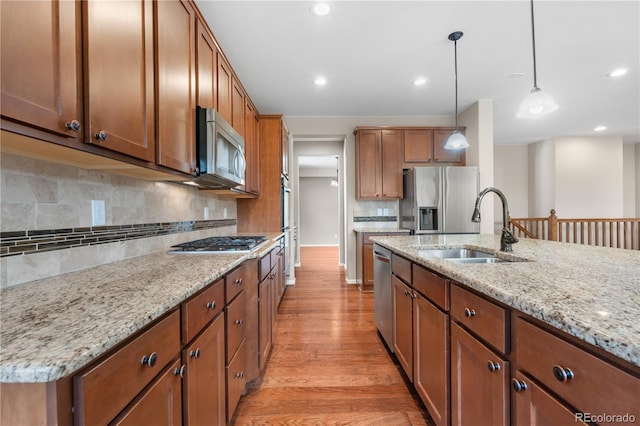 3995 Manorbrier Cir, Castle Rock, CO 80104 - kitchen with appliances with stainless steel finishes, a sink, light wood finished floors, brown cabinetry, and recessed lighting
