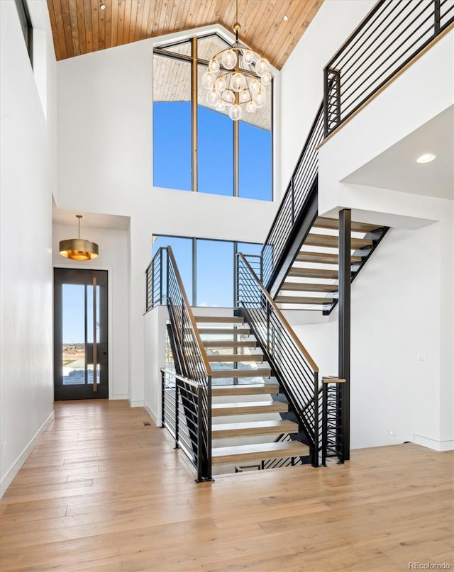 stairs featuring a chandelier, high vaulted ceiling, wood ceiling, and wood-type flooring